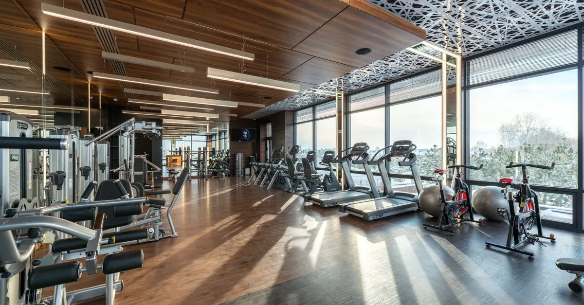 Modern fitness club interior with treadmills, bikes, and equipment on a wooden floor, the kind of space a gym website is built to sell.