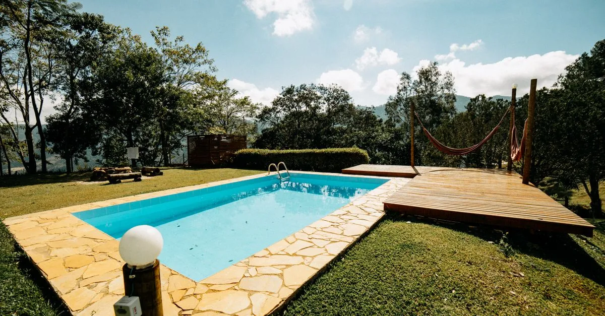 A finished in-ground backyard pool with a wooden deck and lush landscaping, the kind of build local SEO for pool companies helps get found.