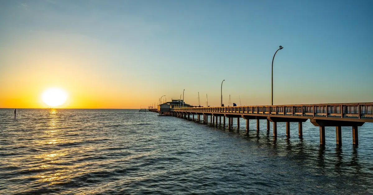 A wooden pier reaching into Mobile Bay at sunset from the Eastern Shore of Alabama, the Gulf Coast waterfront the Mobile area is built around.