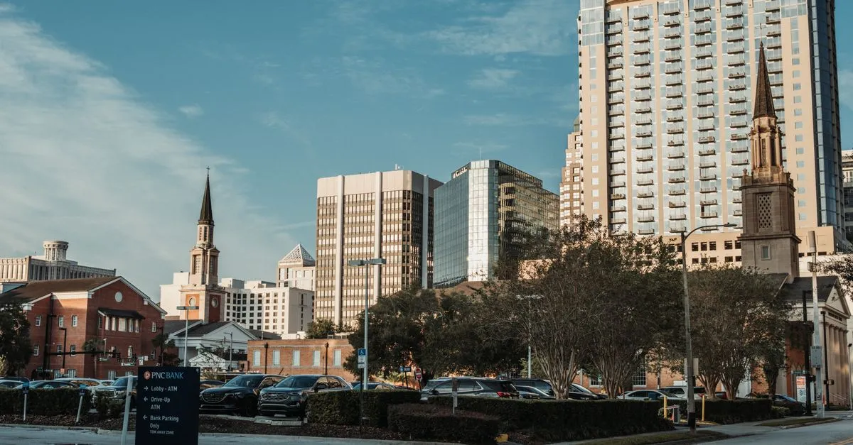 Downtown skyline of a mid-sized American city with office towers and church steeples under a blue sky.