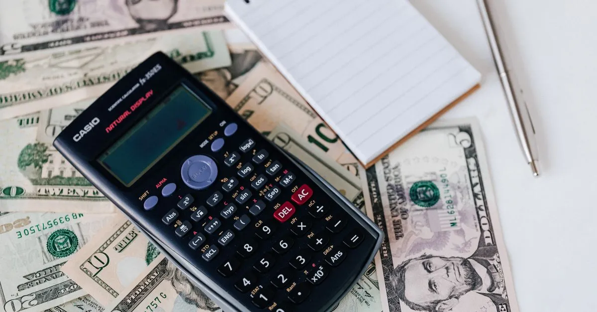 A calculator and notepad on cash, representing the cost of answer engine optimization.