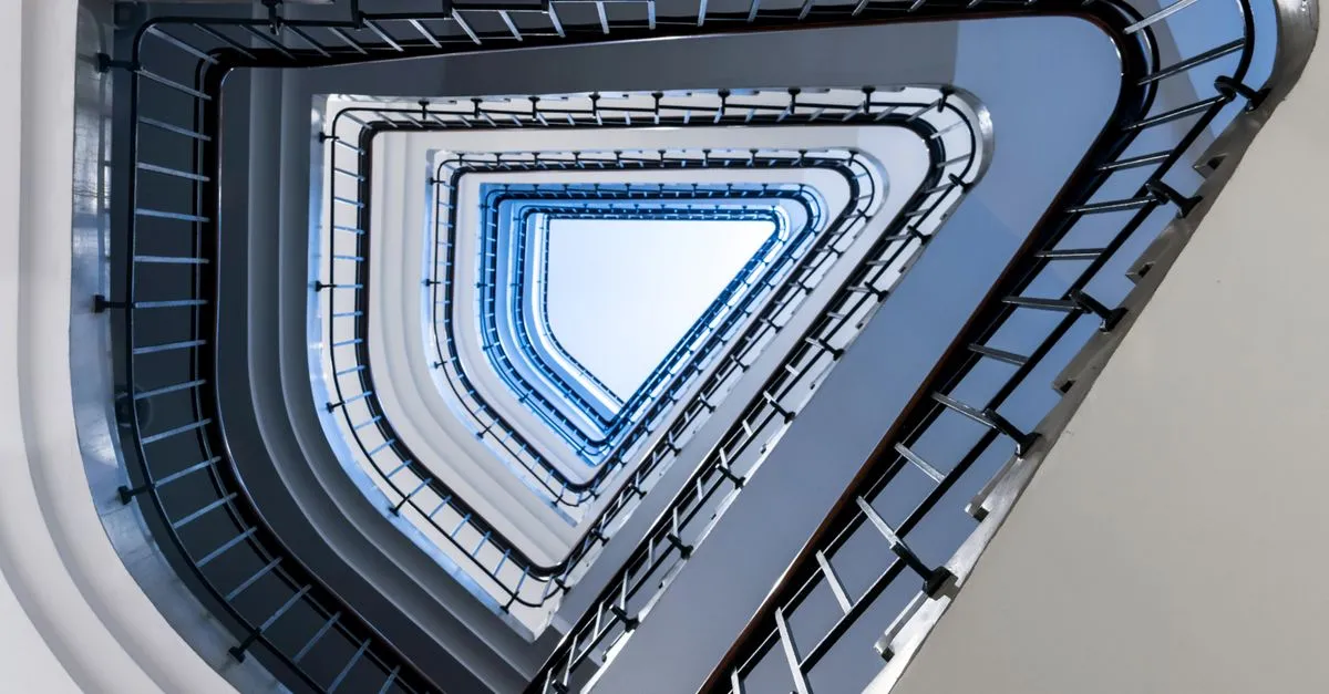 Looking up a triangular spiral staircase that folds back on itself, standing in for a redirect loop.