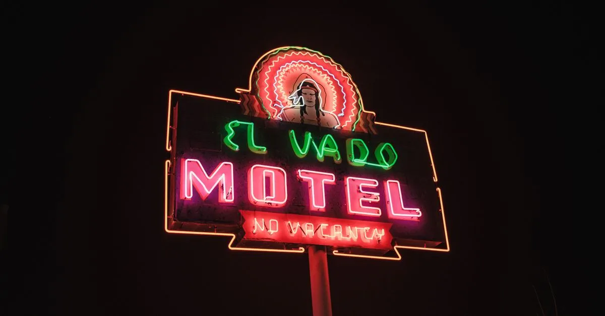 The restored El Vado Motel neon sign glowing at night along Route 66 in Albuquerque, New Mexico, a local landmark now surrounded by businesses that compete online.