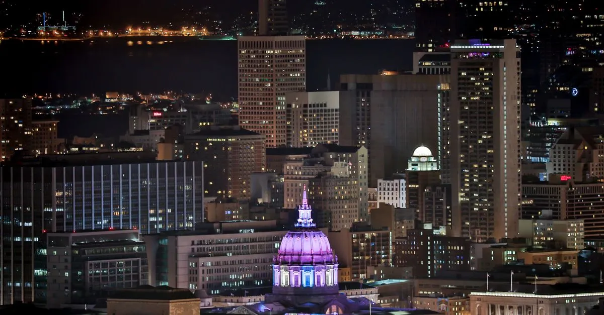 The San Francisco skyline at night with the illuminated City Hall dome glowing above the downtown grid, the dense and compact market where the local map pack is won.