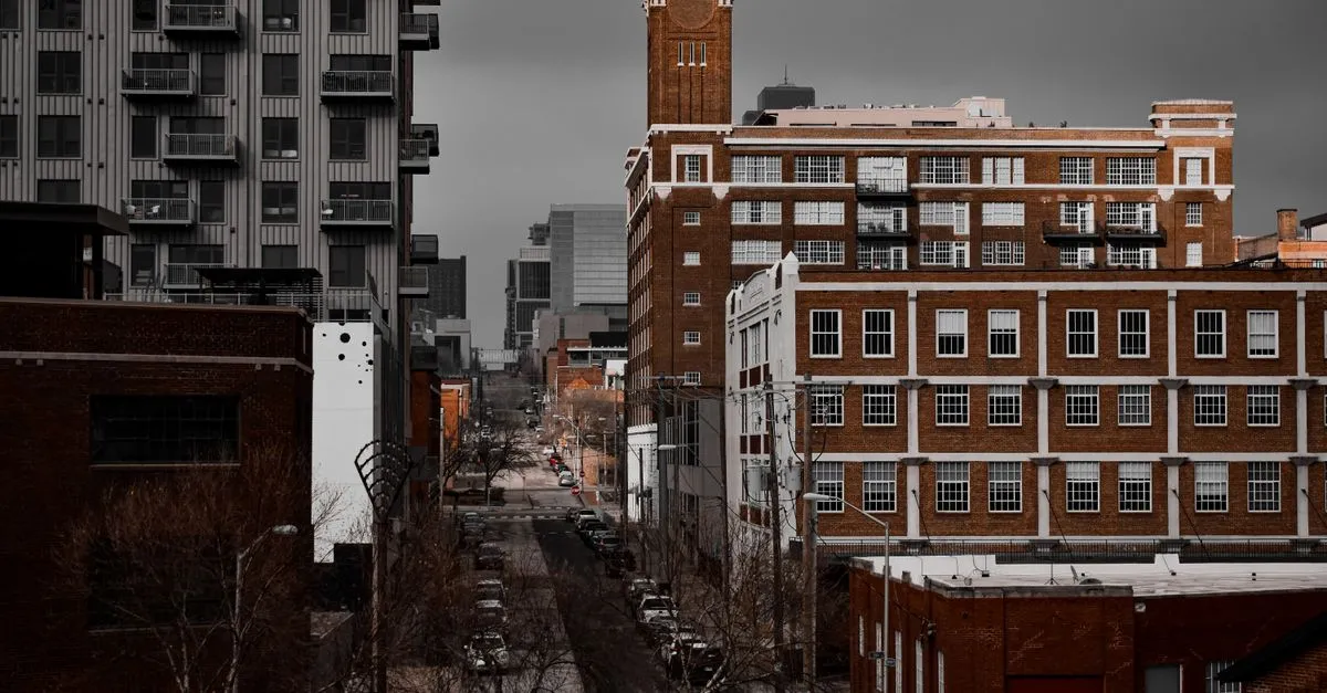 A dense Kansas City, Missouri street lined with historic brick buildings and modern apartment blocks under a cloudy sky.