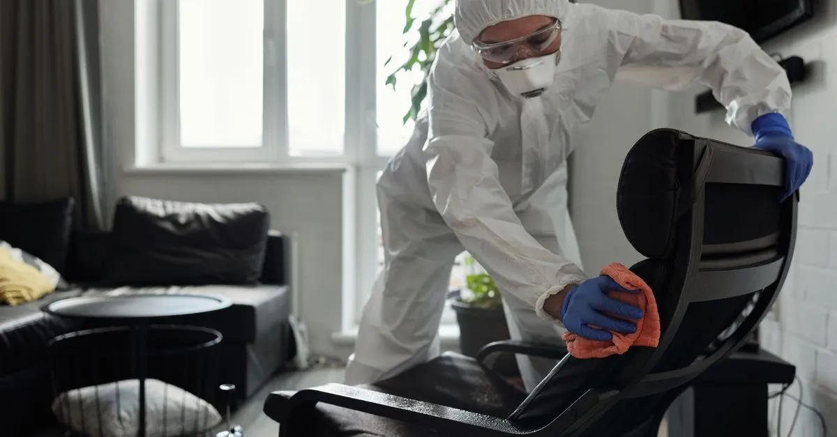A house cleaner wiping down an armchair while cleaning a home interior, the kind of maid service local SEO for house cleaners helps get found.