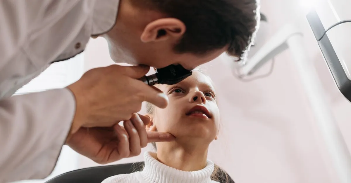 Optometrist examining a young patient's eyes during an eye exam at the practice.