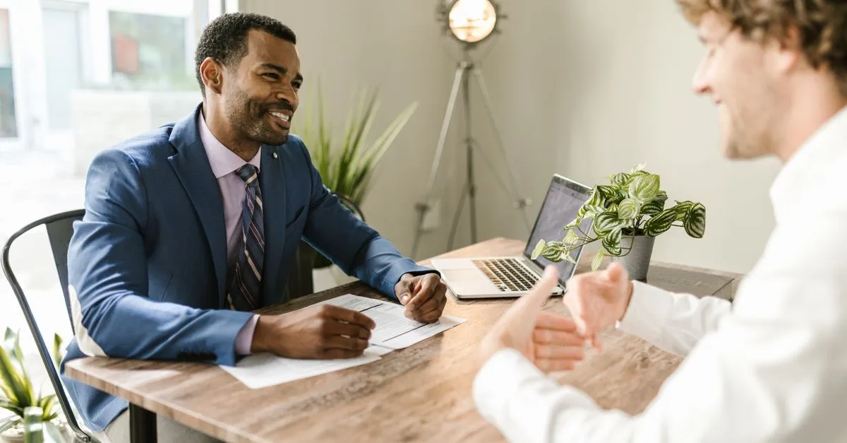 A local insurance agent going over coverage with a client across the desk in his office, the kind of agency clients find when they search for an insurance agent near me.