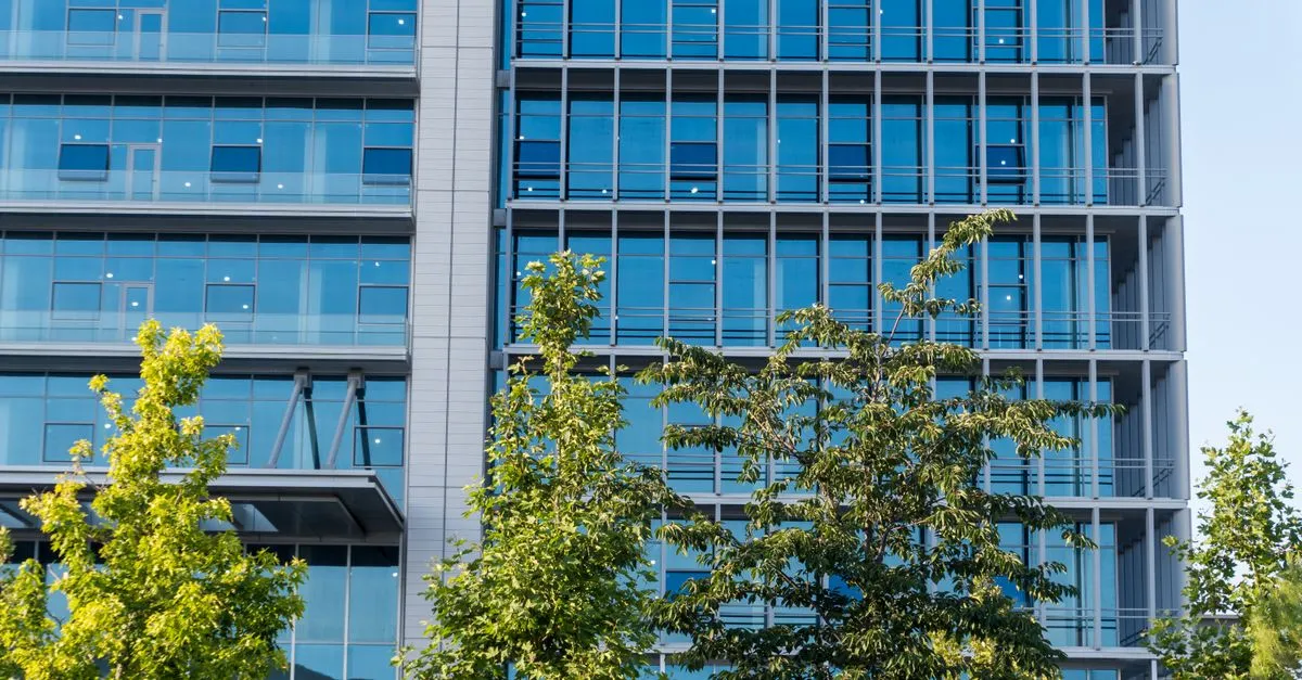 A modern glass office building framed by green trees, the kind of tech campus common across San Jose and Silicon Valley.