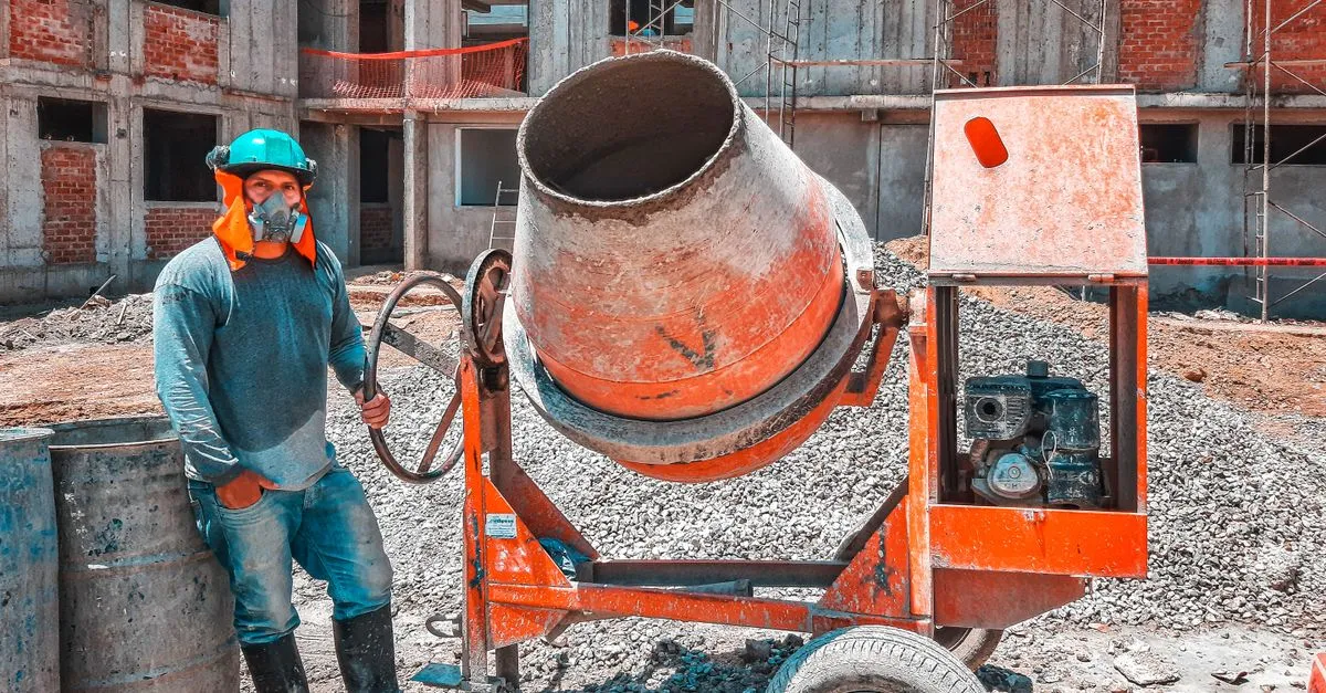 A construction worker operating a concrete mixer at an active building site, the kind of work a construction company website is built to showcase.