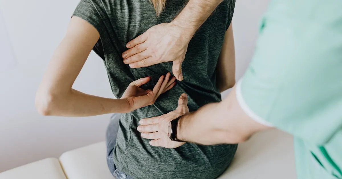 A chiropractor examining the back of a patient in a clinic, the kind of practice local SEO for chiropractors helps get found.