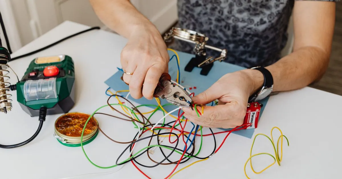 An electrician strips and organizes colored wires with pliers, the kind of pro local SEO for electricians helps get found.