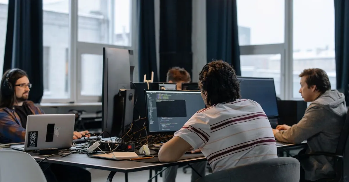 A SaaS product team of developers working at computers building software in a modern office.