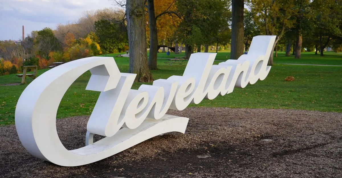 The white Cleveland script sign standing in Edgewater Park with fall color, where local businesses compete for attention online.