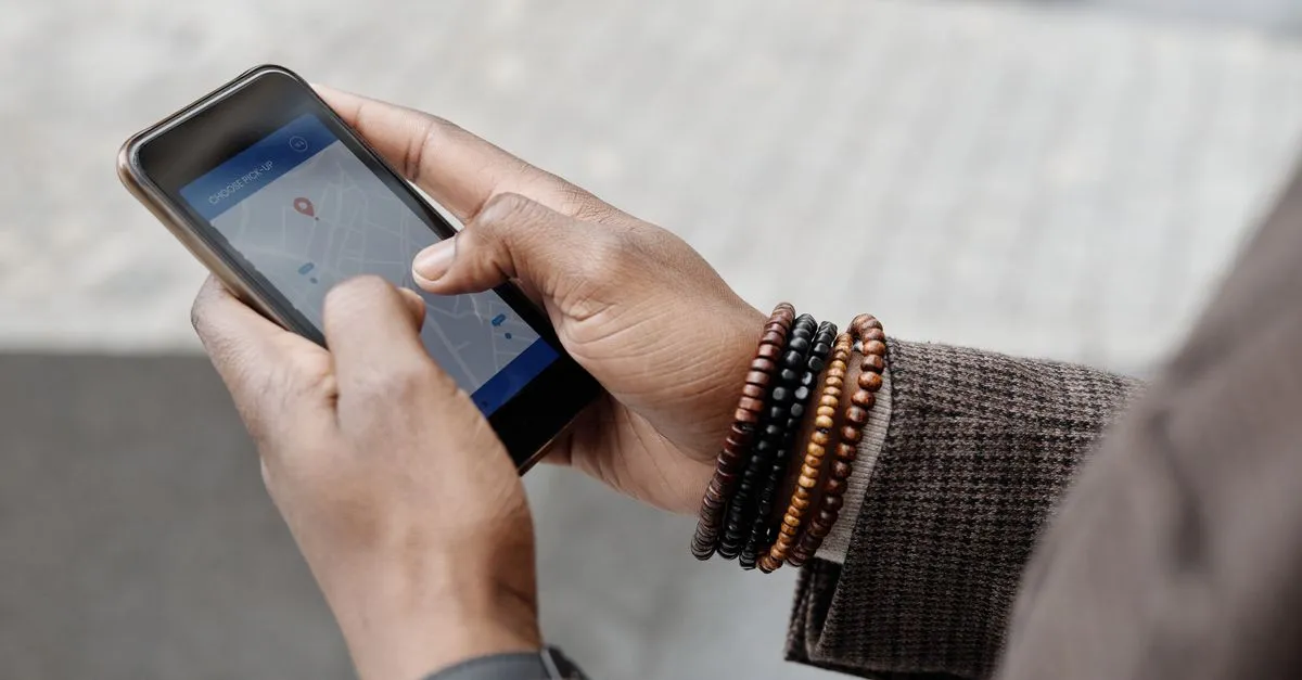 A hand holding a phone using a maps app to find a local business.