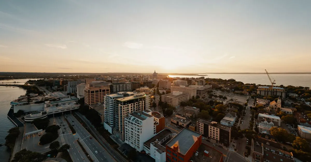 An aerial view of downtown Madison, Wisconsin at sunset, with the State Capitol dome on the isthmus between Lake Mendota and Lake Monona.