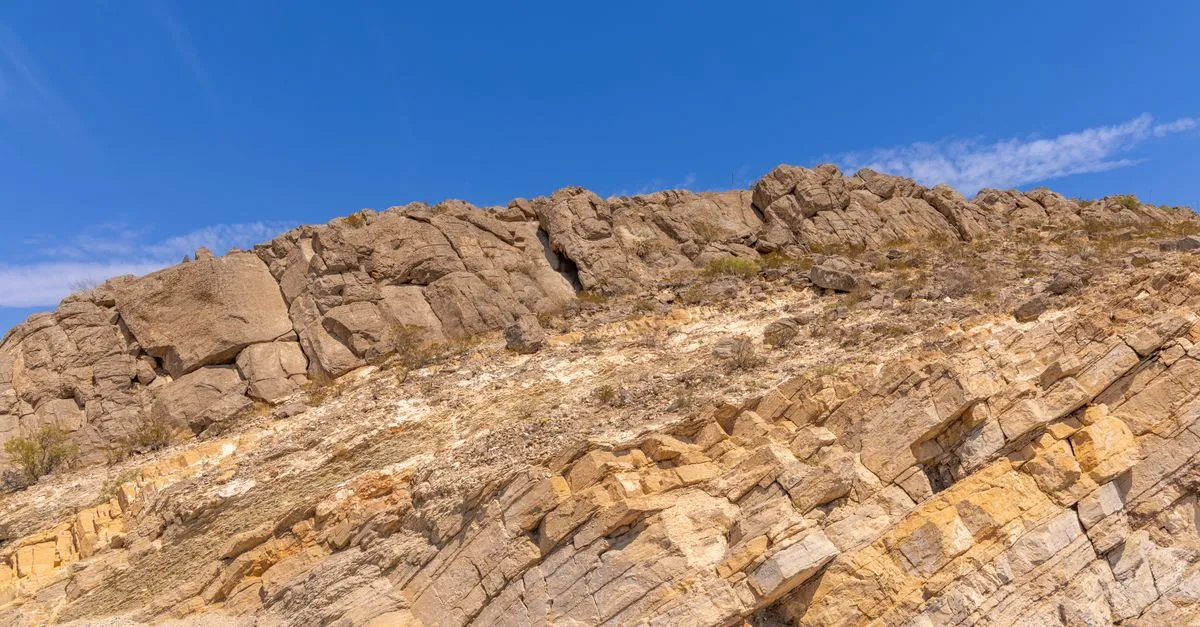 A rugged, rocky mountainside rising under a clear blue sky in the arid desert around El Paso, Texas.