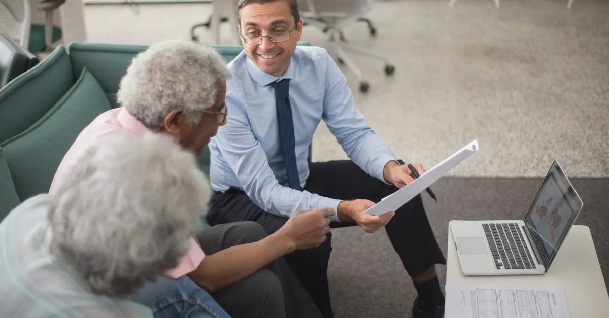 An insurance agent going over a policy with clients in an office, the kind of independent agency SEO for insurance brokers helps get found.
