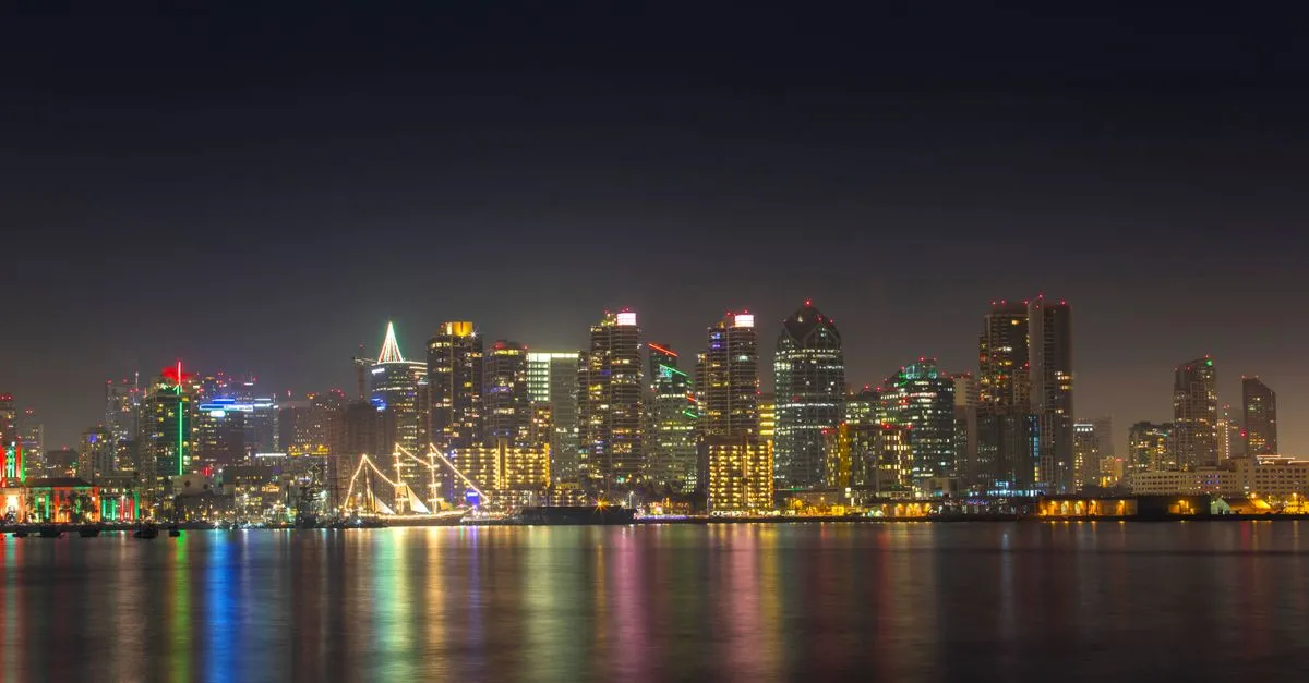 The San Diego skyline lit up at night over the calm water of the bay, the coastal market where the local map pack is won.