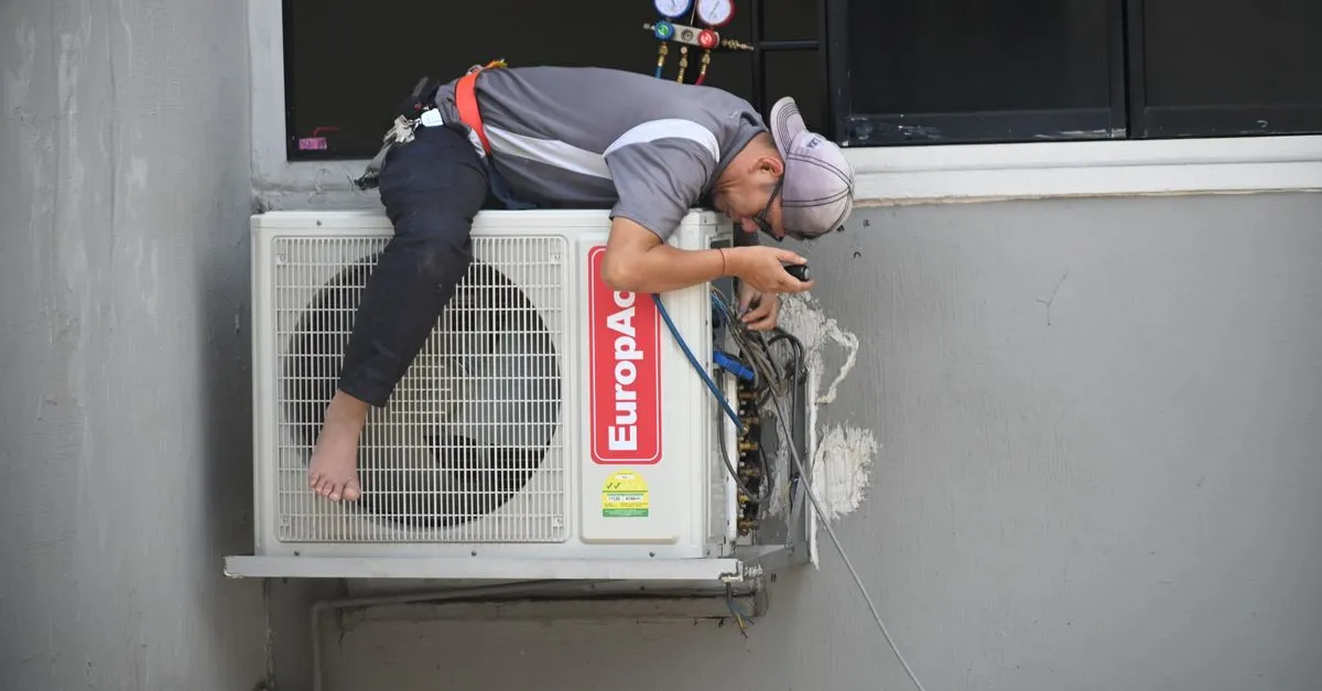 An HVAC technician repairing an outdoor air conditioning unit, the kind of company HVAC SEO helps get found.