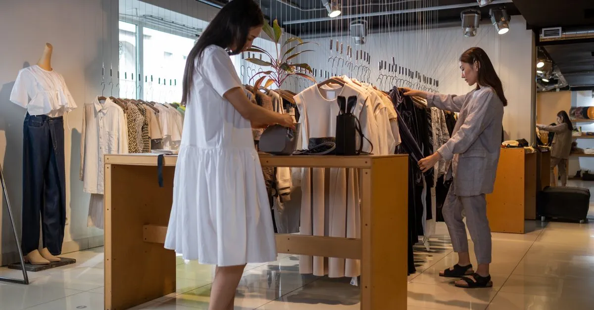 Two women browsing clothes inside a modern retail store, the kind of shoppers a retail SEO agency helps find your storefront.