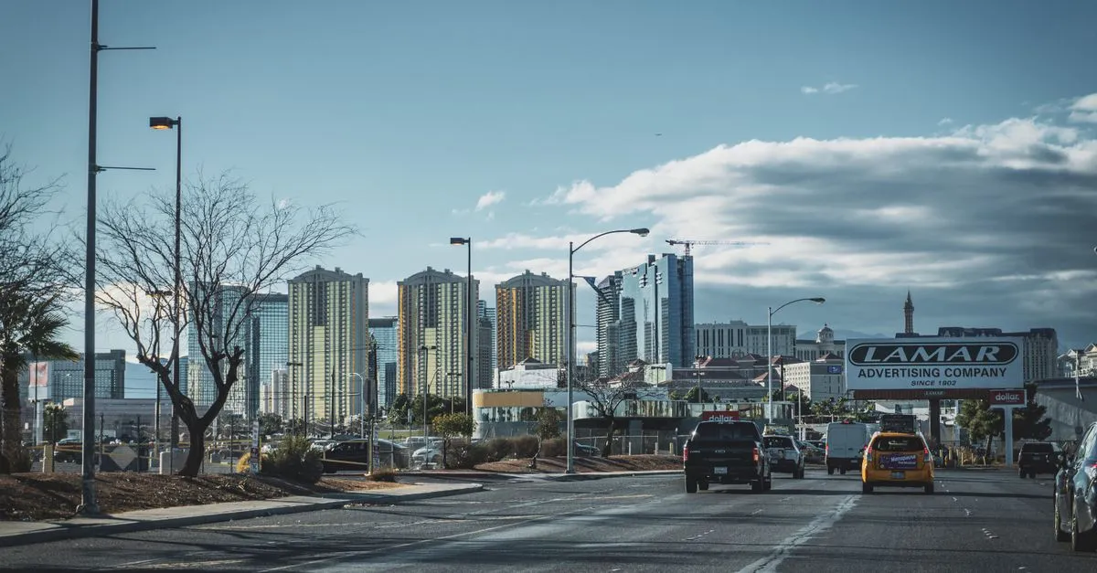 A wide Las Vegas street with traffic and streetlights leading toward the valley high-rises, the everyday locals' side of the city where the map pack is won.