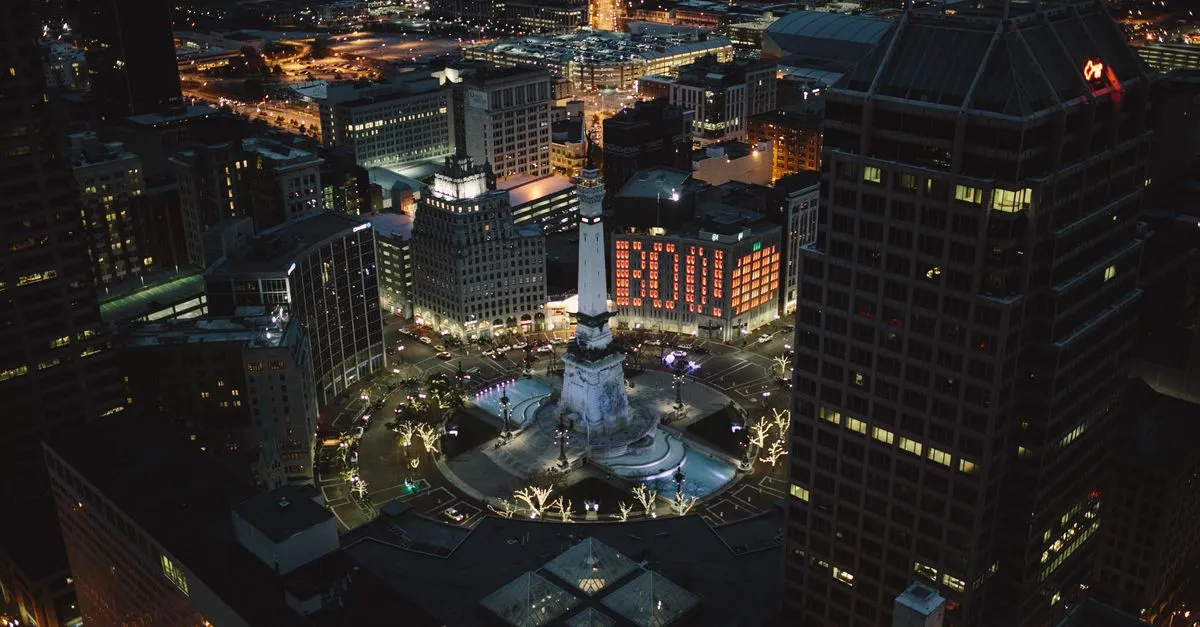 Aerial night view of Monument Circle in downtown Indianapolis, Indiana, with the Soldiers and Sailors Monument lit up and city lights around it.