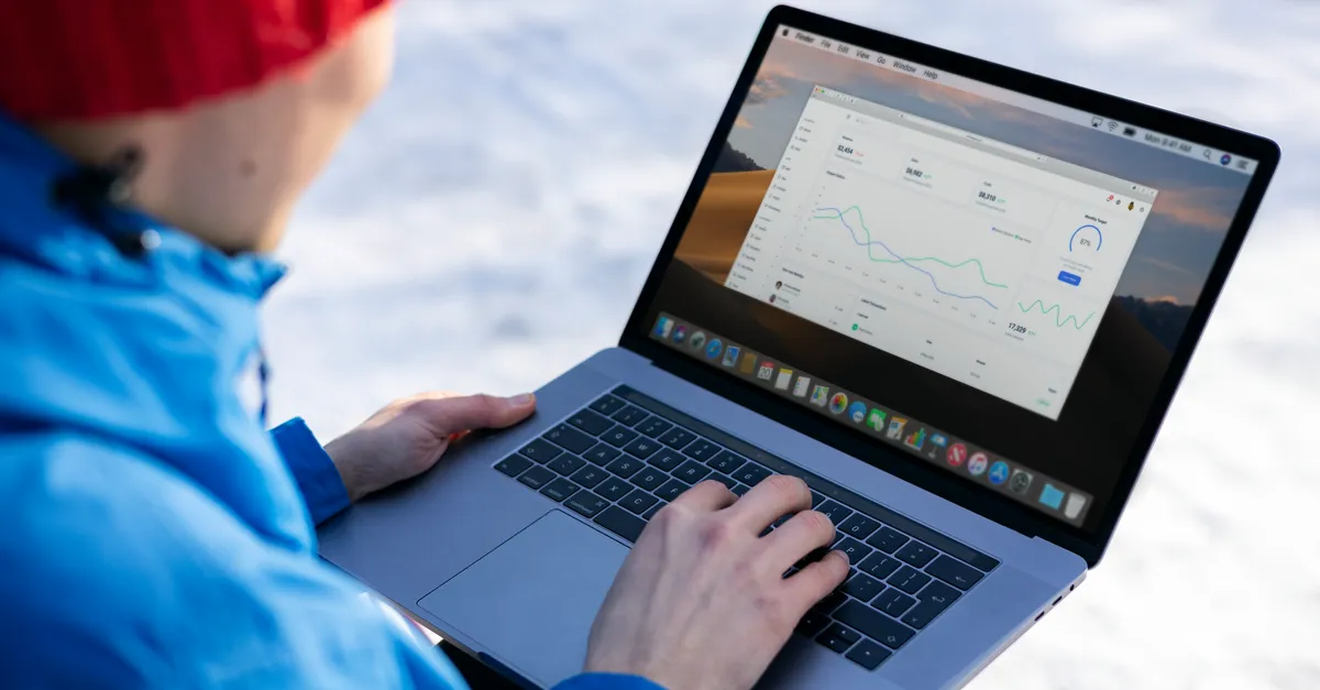 A person reviewing website traffic charts on a laptop while working outside.