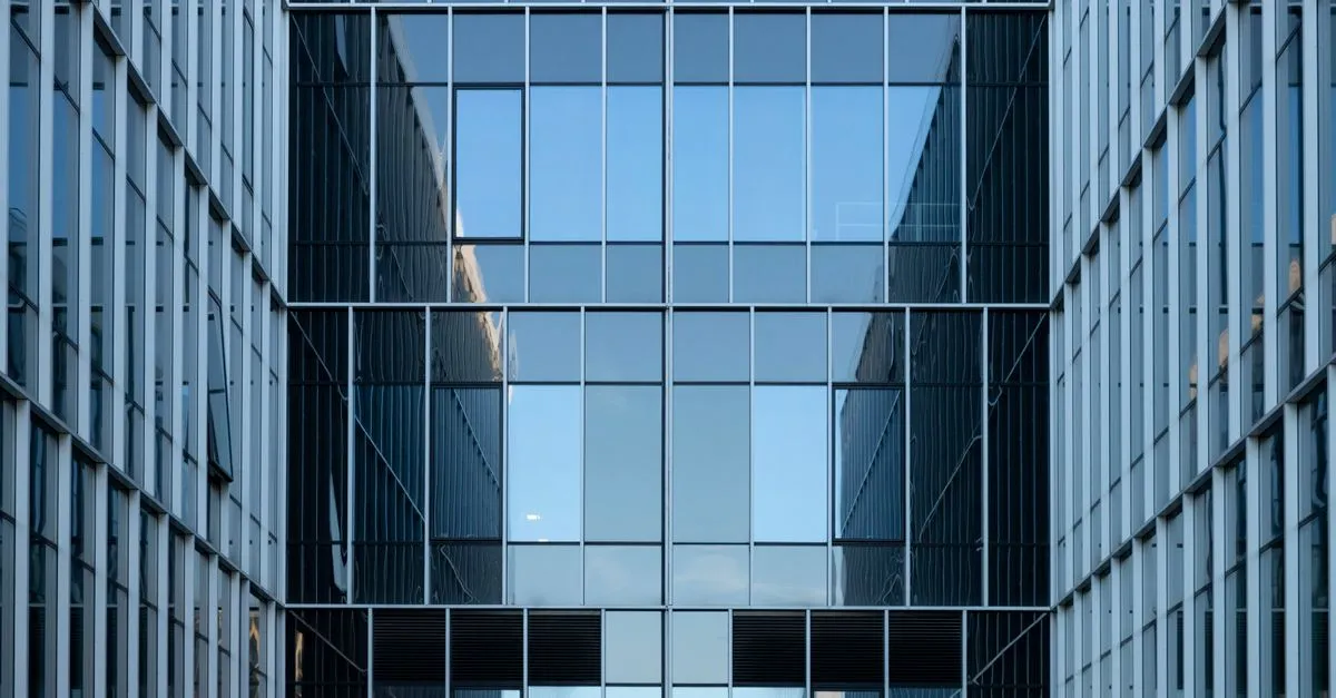 A contemporary corporate office facade of reflective blue glass, the kind of polished workplace common across Plano business districts.