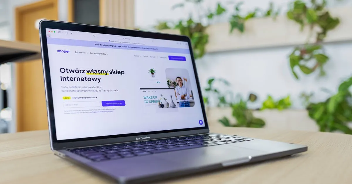 A laptop on a wooden desk showing an e-commerce homepage with a large headline, short subhead, and a call-to-action button above the fold.
