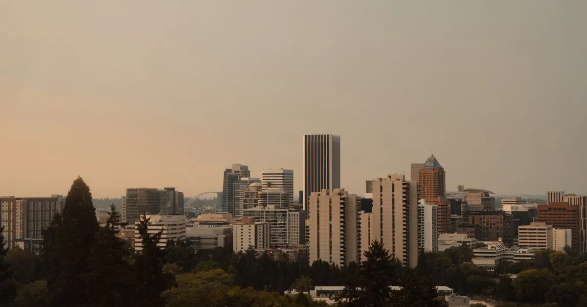 The Portland, Oregon skyline framed by evergreens at sunset, where local brands compete for attention online.