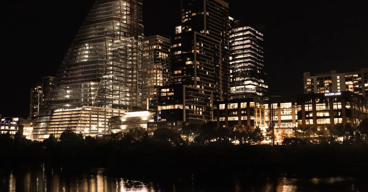 Illuminated downtown Austin, Texas skyline reflected in the river at night.