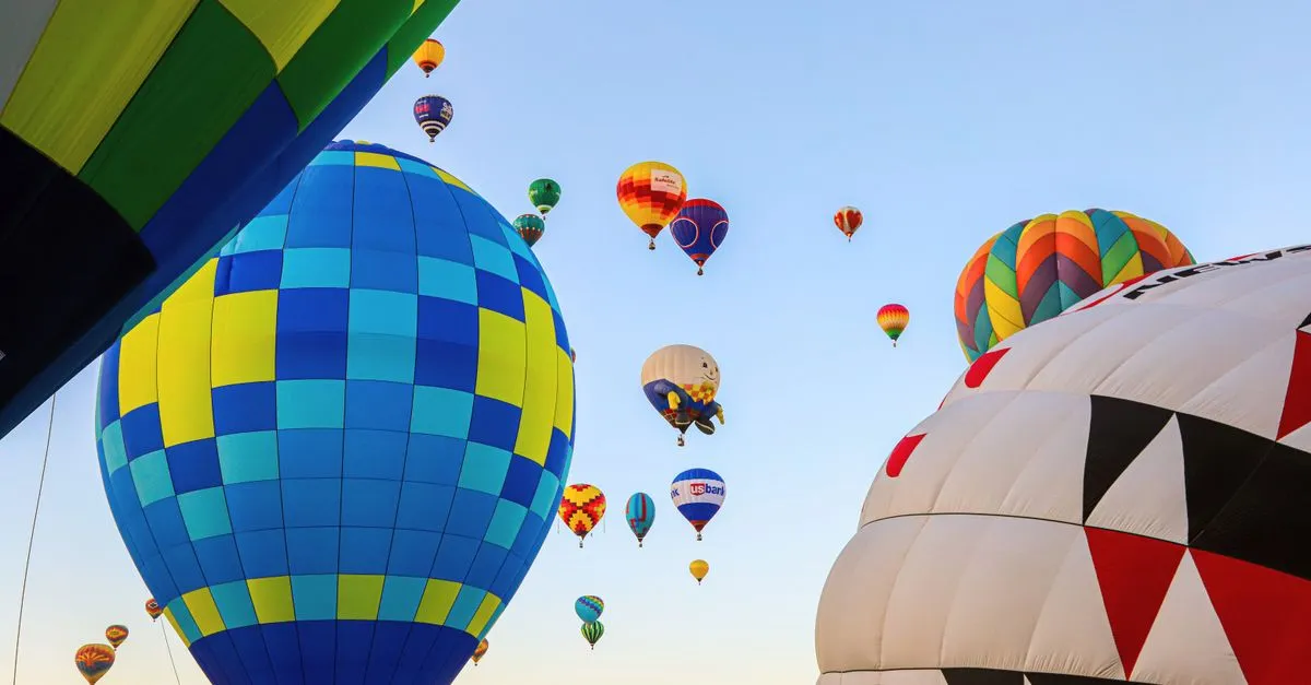 A vibrant display of hot air balloons soaring at dawn during the Balloon Fiesta in Albuquerque, New Mexico.