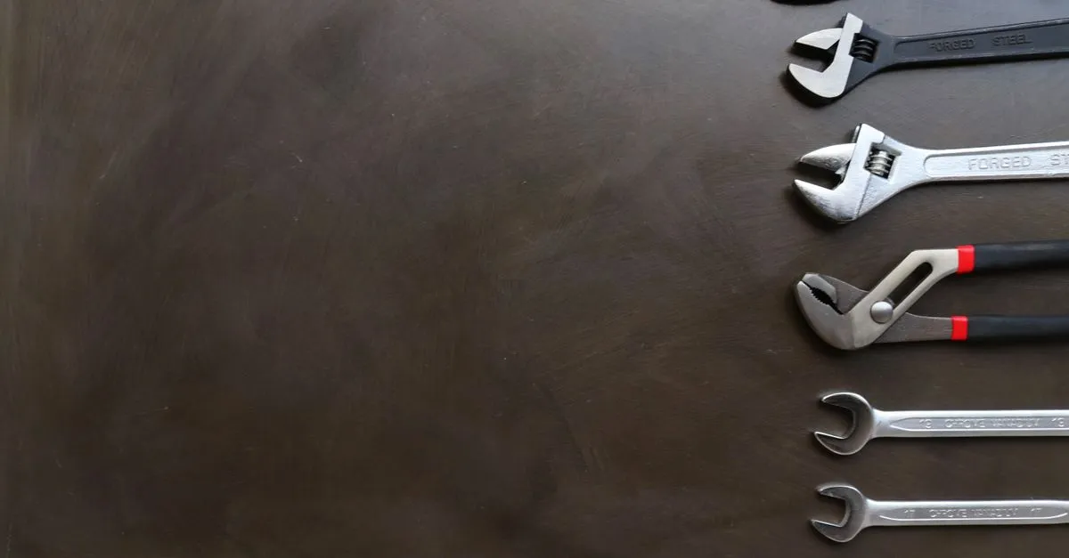 Plumbing wrenches laid out on a dark workbench, the tools behind the jobs a plumber website is built to book.