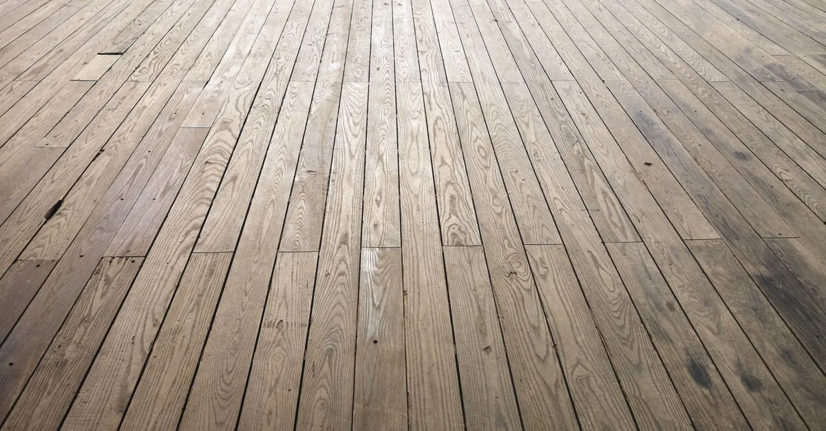 A wide angle view of freshly laid hardwood floor planks running the length of a room, showing natural wood grain.
