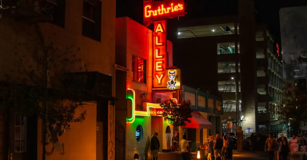 The glowing neon sign of Guthrie's Alley Cat over a downtown Bakersfield, California street at night, where local businesses compete for attention online.