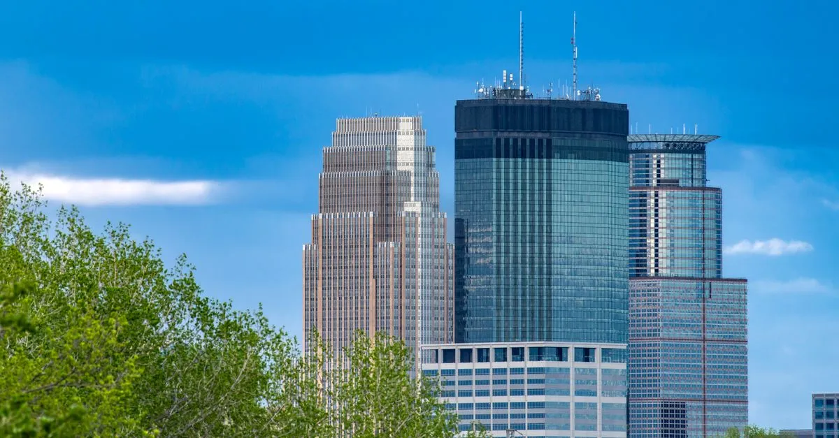 Downtown Minneapolis, Minnesota skyline with its office towers rising above green summer trees.