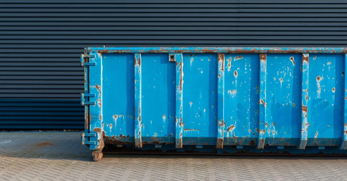 A large blue roll-off dumpster parked on a paved surface, ready for a rental drop-off.