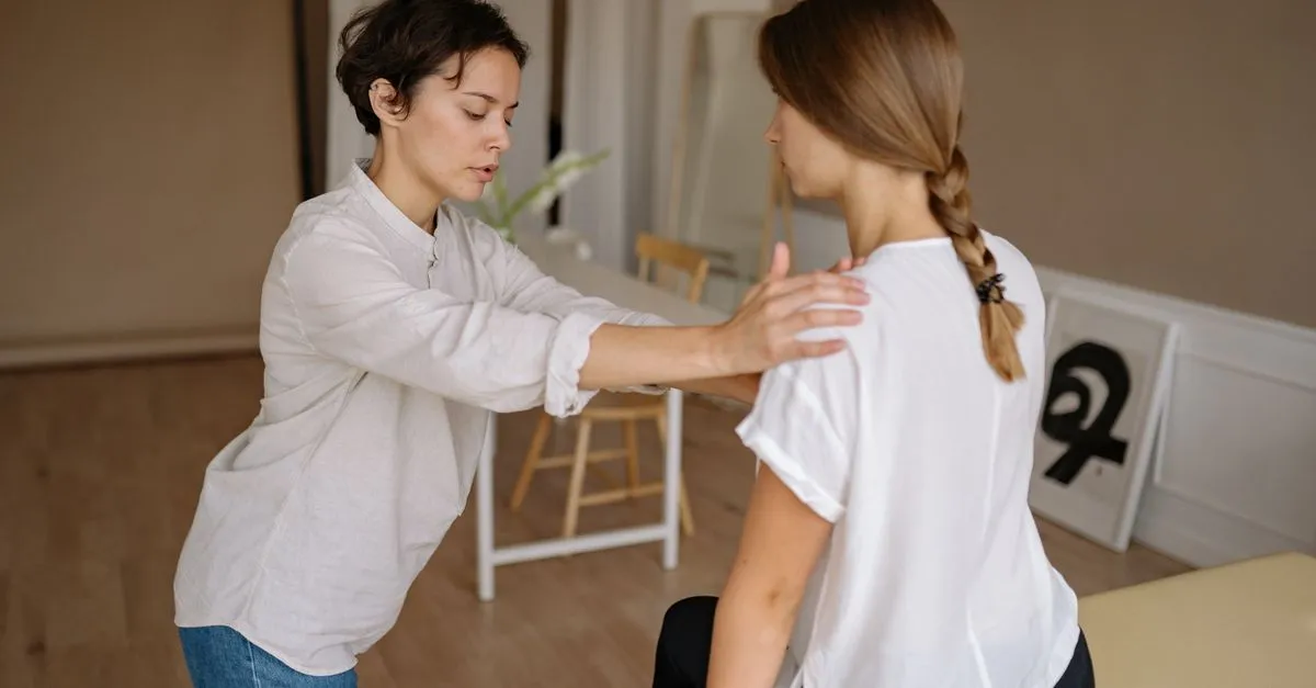 A chiropractor assessing the posture and upper back of a seated patient in a clinic, the kind of care SEO for chiropractors helps researching patients find.