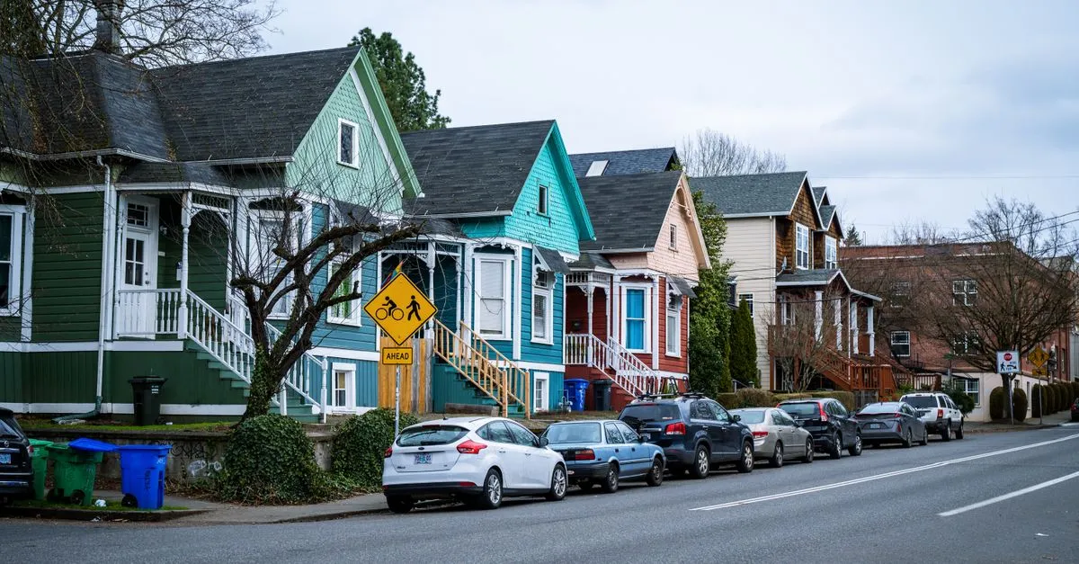 A row of colorful old Portland, Oregon houses along a neighborhood street with a bike-and-pedestrian crossing sign, the kind of walkable district where the local map pack is won.