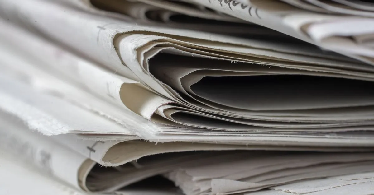 Close-up of a stack of folded newspapers, representing the third-party press and mentions that build a brand Perplexity trusts.