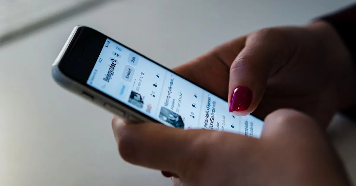 A hand holding a smartphone and scrolling through an app's interface with a pinned top navigation bar.