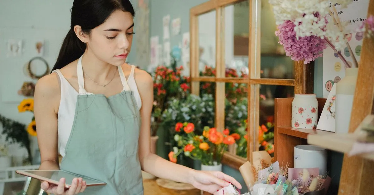 A local florist checking orders on a tablet in her shop.