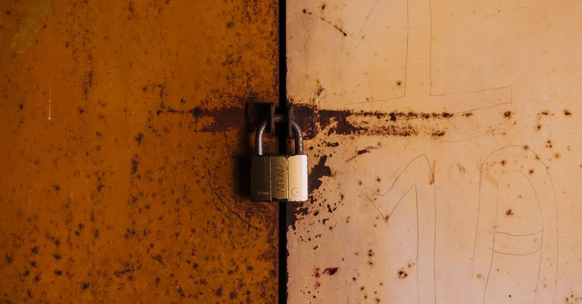 A brass padlock locking a pair of weathered, rusty metal doors, standing in for the site security that prevents most negative SEO damage.