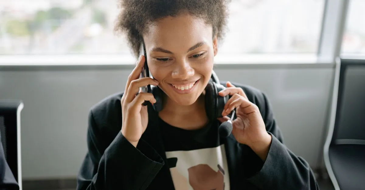 A support agent wearing a headset smiles while taking a call, the way a good reply to a customer sounds when it is written by a real person.