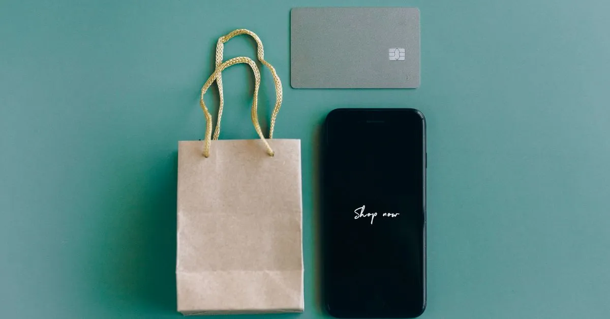 Overhead view of a smartphone, credit card, and shopping bag, representing mobile shopping and product reviews.
