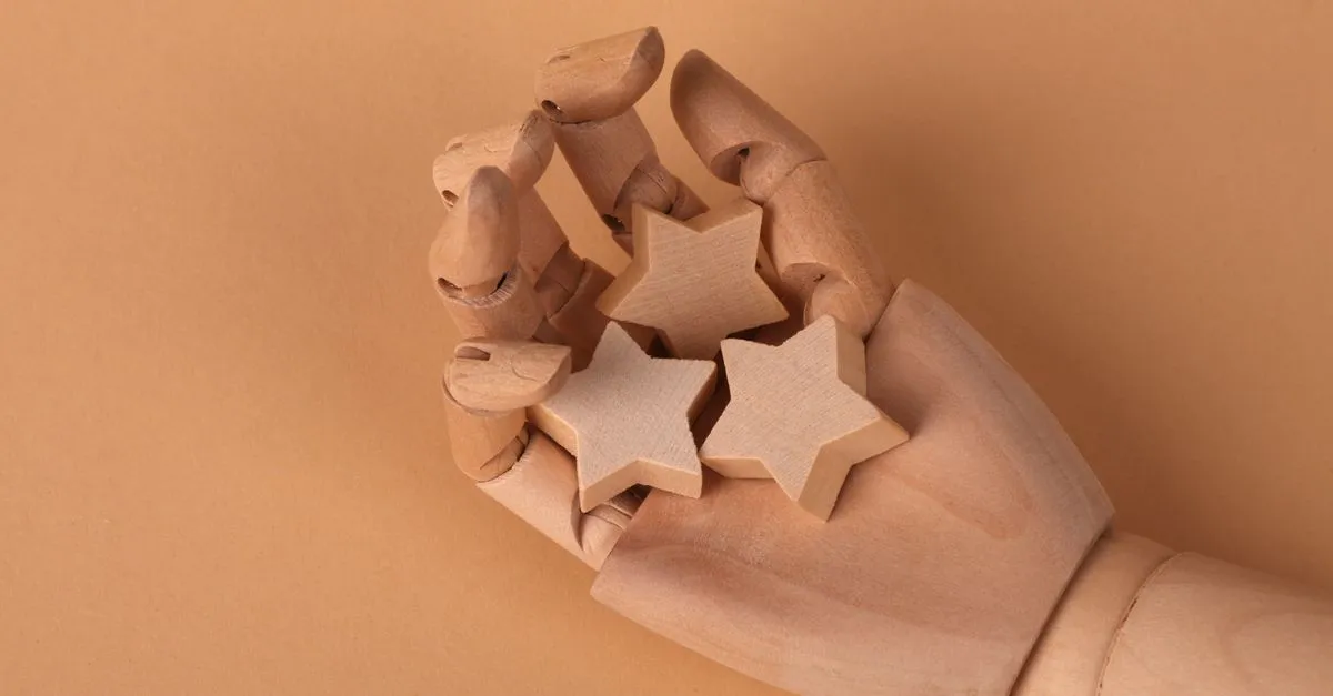 A wooden mannequin hand holding three small wooden stars against a beige background.