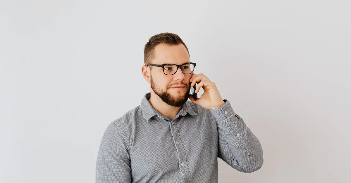 A man wearing glasses talking on a mobile phone, the kind of quick call that turns into a customer review.