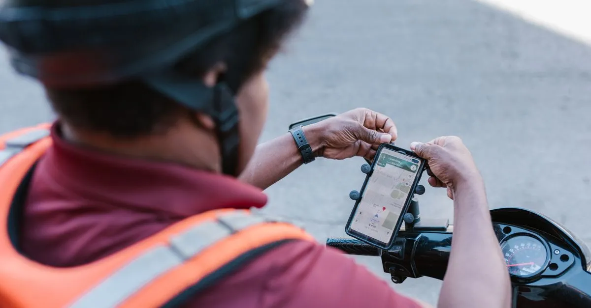 A rider checking a phone mounted for navigation, evoking routes between locations.