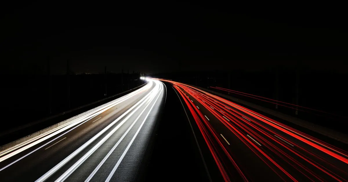 Long-exposure light trails from cars streaking along a dark highway at night, representing fast page loading.